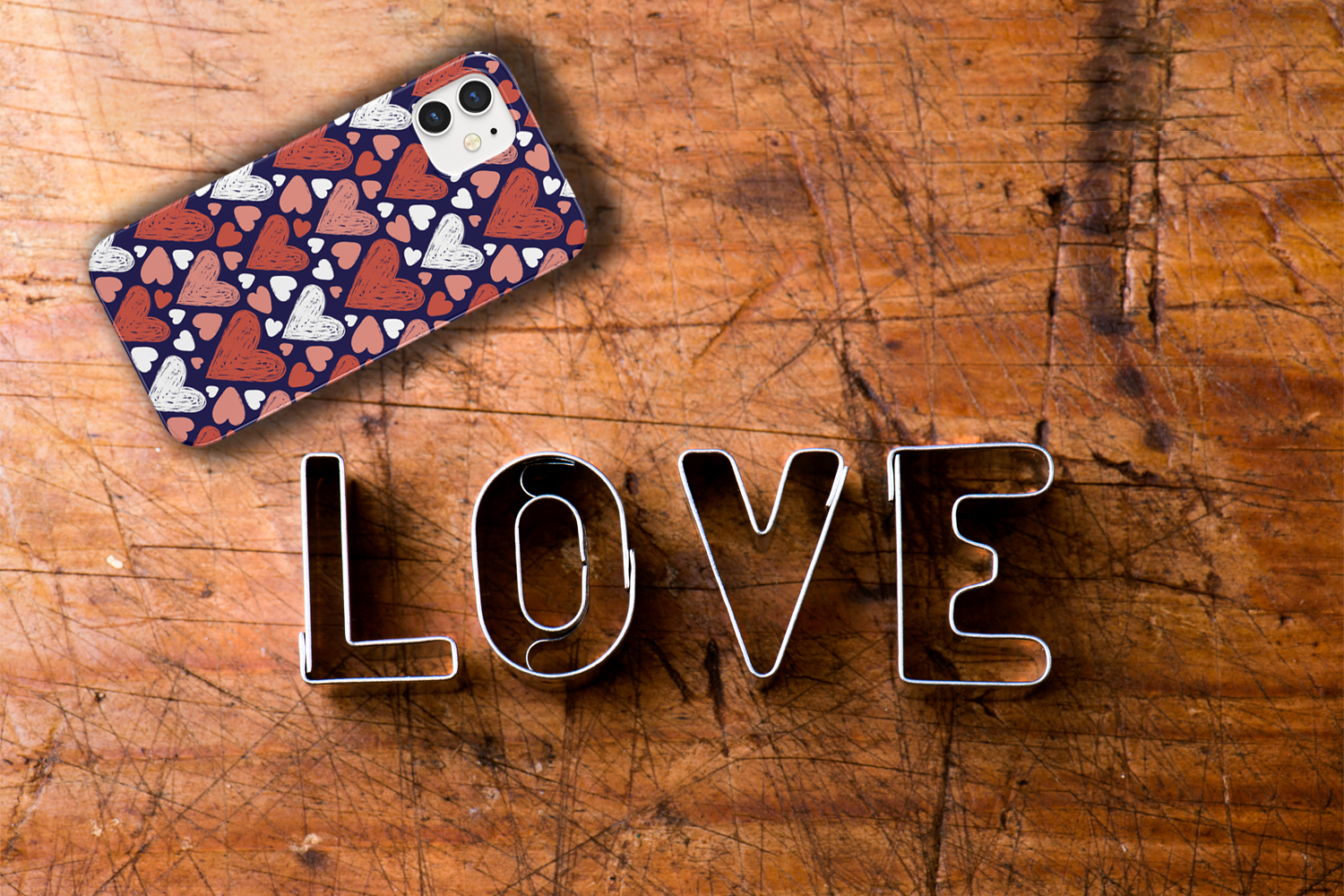 A table with an iPhone with a Sketchy Love Hearts Phone Case and a sign that reads LOVE.