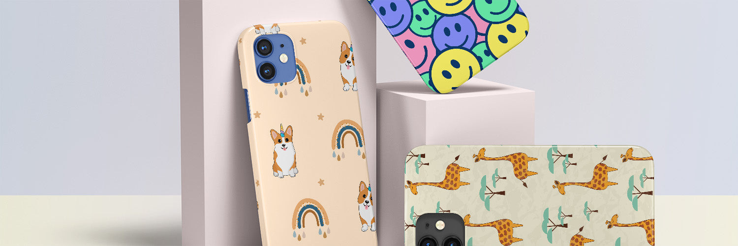 Three iPhones, one with a smiley face case, one with a unicorn corgi case, and one with a giraffe case